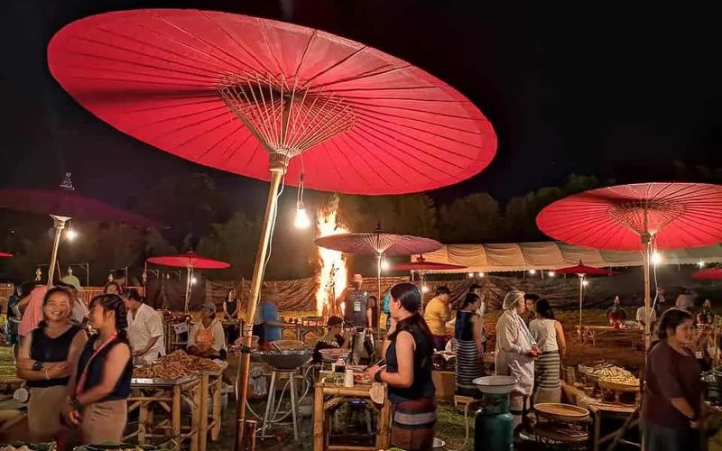 Vibrant night market in Chiang Mai during Yi Peng Festival with red umbrellas, local stalls, and crowds enjoying the festive atmosphere