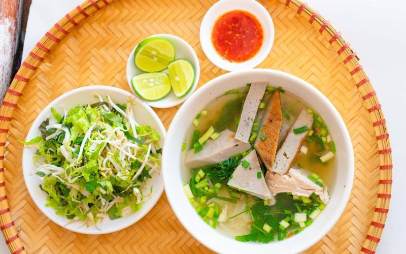 Traditional Nha Trang fish cake noodles served with fresh herbs, lime, and chili sauce in Vietnam