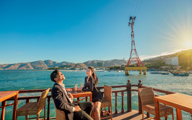 Couple enjoying a luxury yacht tour in Nha Trang Bay with sunset view and cable car in the background