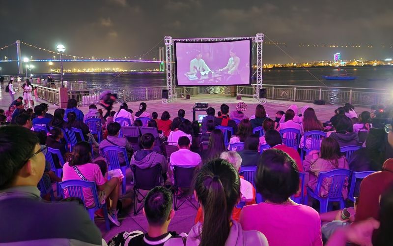 Crowd enjoying an outdoor cinema night by the Han River in Da Nang, Vietnam – a unique summer cultural experience for locals and tourists