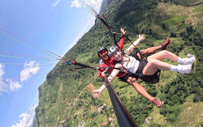 Tandem paragliding over green countryside and hills in Kampot, Cambodia.