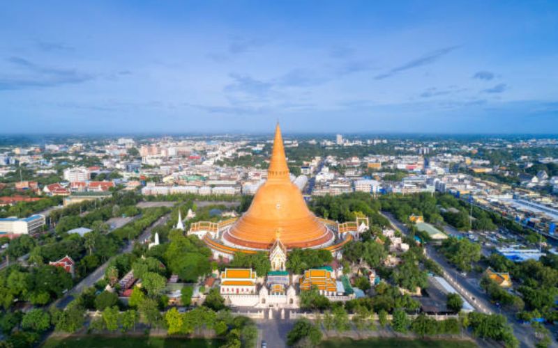 Aerial view of Phra Pathom Chedi, the world's tallest stupa, towering over the city of Nakhon Pathom, surrounded by greenery and urban landscape