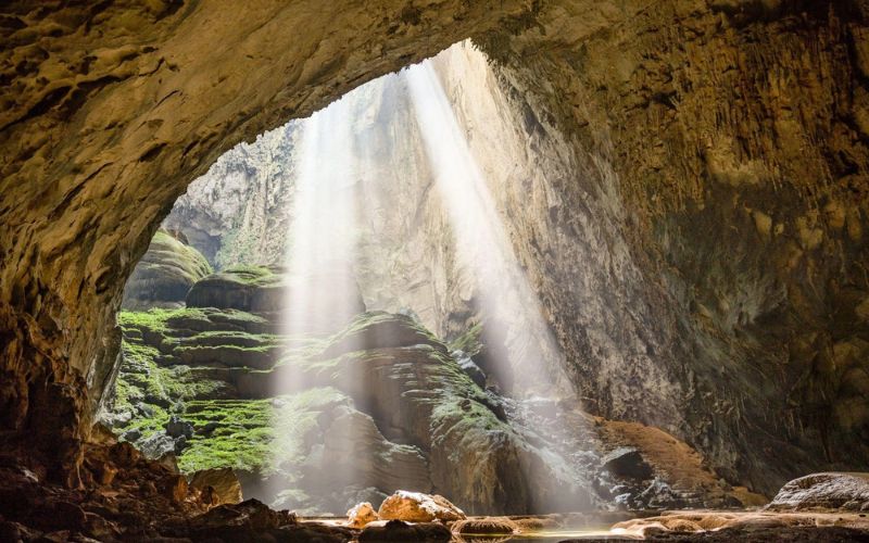 Sunlight beams into Son Doong Cave in Phong Nha-Ke Bang National Park, Vietnam, revealing lush greenery inside