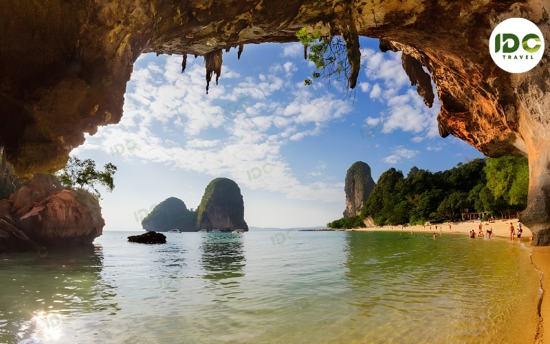 View from inside a limestone cave onto Phra Nang Cave Beach in Krabi, Thailand, with karst islands offshore.