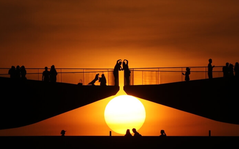 A couple standing at the center of Phu Quoc’s Kiss Bridge, framed by the dramatic colors of the evening sky.