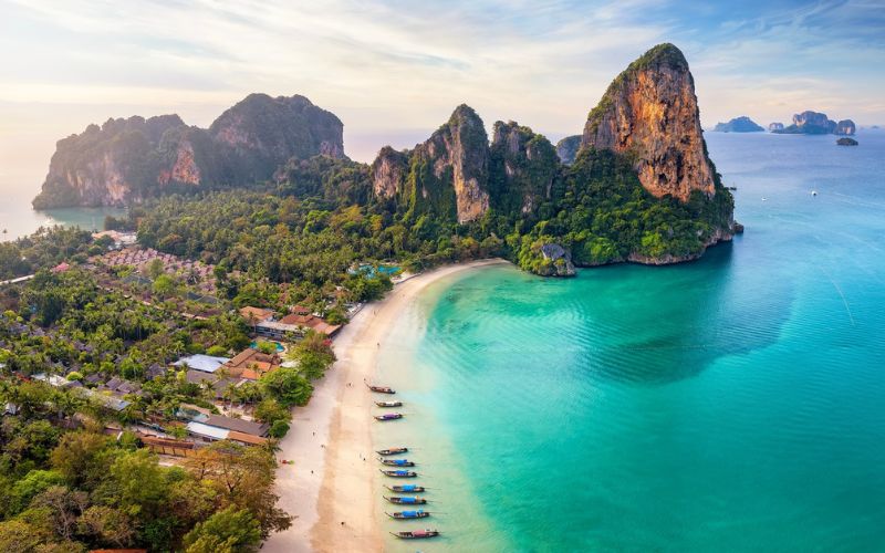 Scenic view of Railay Beach in Krabi, Thailand, with turquoise water, white sand, and towering limestone cliffs