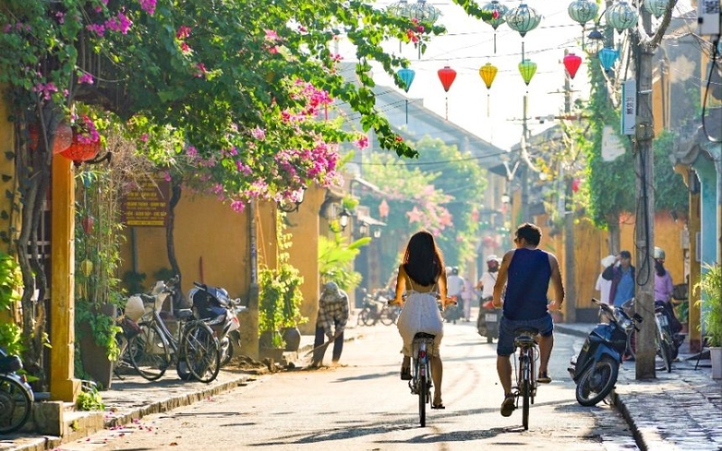 A couple rides side by side through the charming lantern-lit streets of Hoi An, soaking in the town’s romantic atmosphere and timeless beauty, one of Indochina’s most unforgettable experiences for lovers.