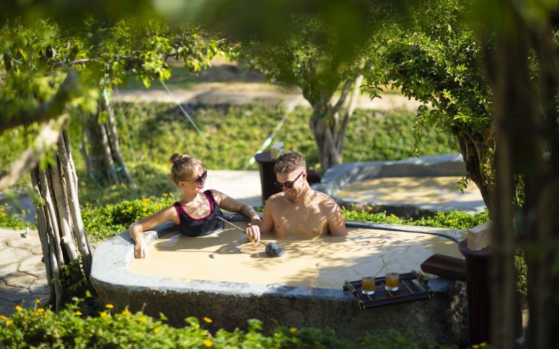 Couple relaxing in a natural mud bath at hot springs wellness resort in Nha Trang, Khanh Hoa
