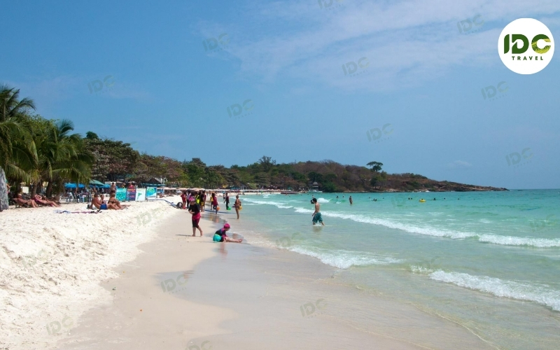 White sand and turquoise water at Sai Kaew Beach on Koh Samet, Thailand, with swimmers and sunbathers along the shore.
