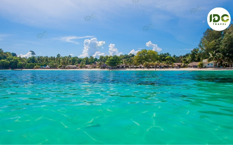 Clear turquoise water and white sand backed by palm trees at Sunrise Beach on Koh Lipe, Thailand.