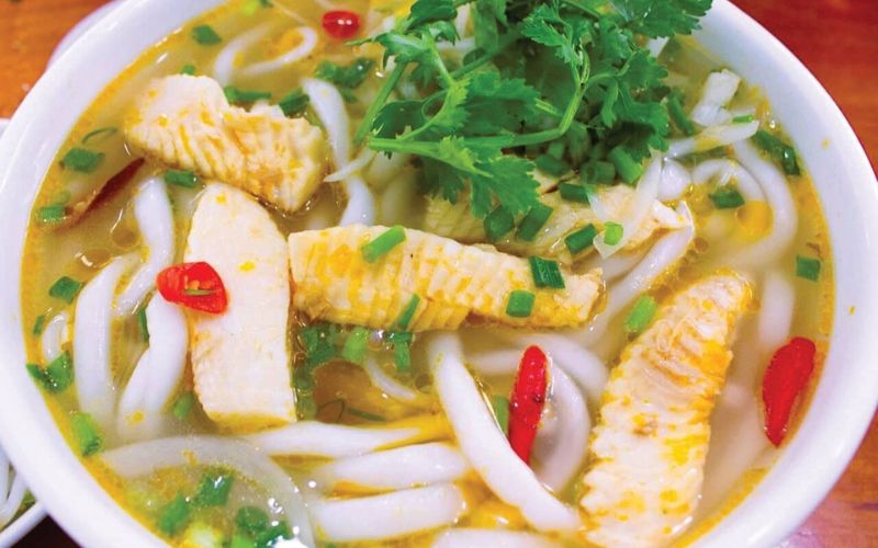 Bowl of Quang Tri snakehead fish thick noodle soup with fresh herbs, chili, and flavorful broth