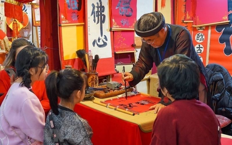 Vietnamese calligrapher writing characters for visitors during the spring pen opening tradition at Tet holiday.