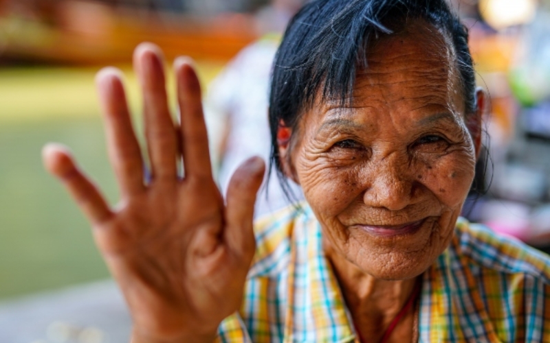 A local vendor at a market in Vietnam waving and saying hello to tourists