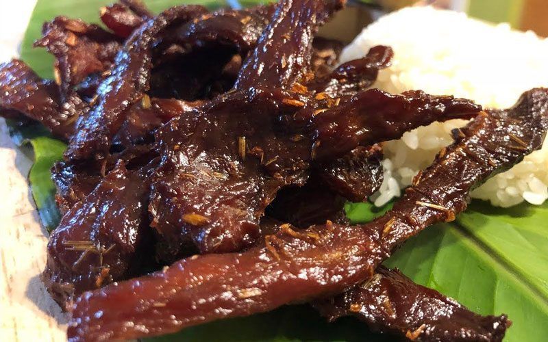 Grilled Lao meat served with sticky rice on banana leaf in traditional style.
