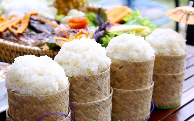 Steamed sticky rice served in traditional bamboo baskets on a wooden table in Laos.