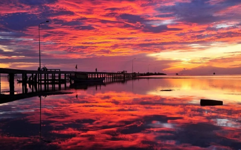Cloud-filled sky glowing in shades of red and purple as the sun sets over Phu Quoc during the rainy season, creating dramatic evening scenery.