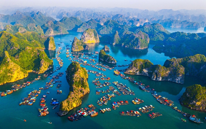 An aerial perspective reveals the stunning natural beauty of Cat Ba Island, where lush green hills meet the turquoise waters of Lan Ha Bay.