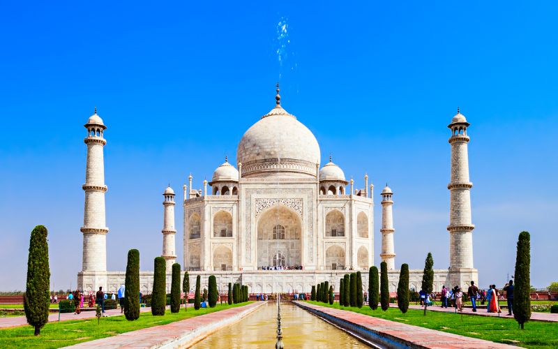 The Taj Mahal in Agra, India, with its white marble dome and minarets under a bright blue sky