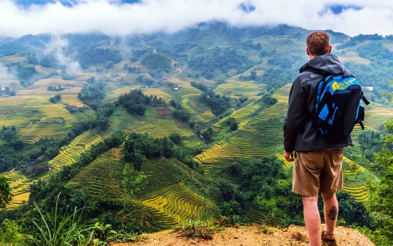 Trekking in Ha Giang through winding mountain trails, with panoramic views of terraced rice fields, limestone peaks, and scattered ethnic minority villages