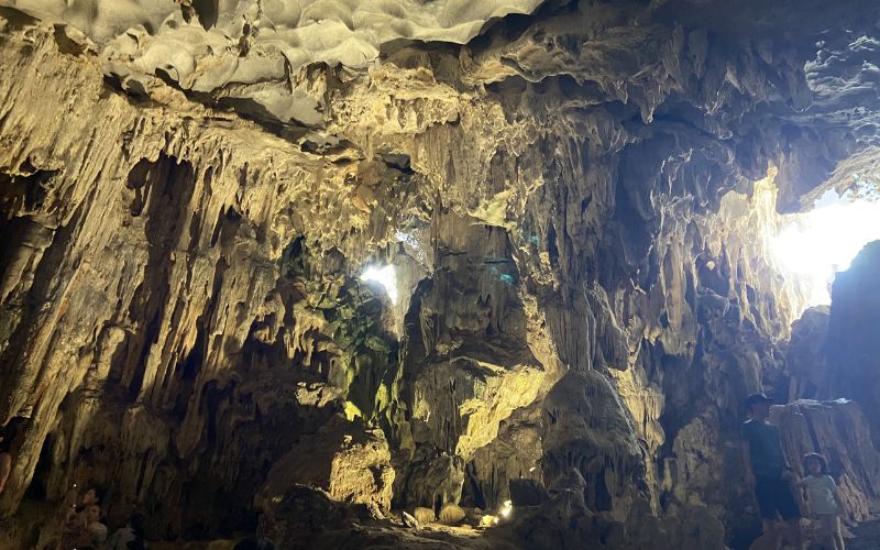 Massive limestone formations inside Sung Sot Cave with natural light filtering through openings above.