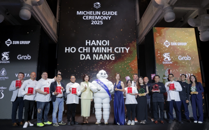 Chefs and restaurant teams from Hanoi, Ho Chi Minh City, and Da Nang pose with Michelin awards alongside the Michelin Man at the 2025 ceremony stage.