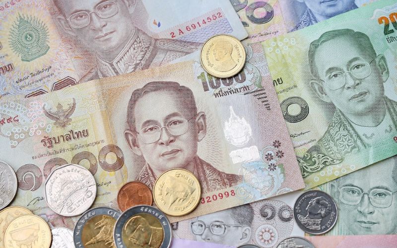 Thai currency including baht banknotes and coins, featuring portraits of King Bhumibol Adulyadej
