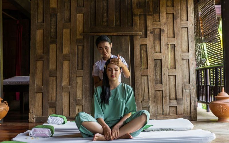 A women receiving a traditional Thai head massage in wooden spa room
