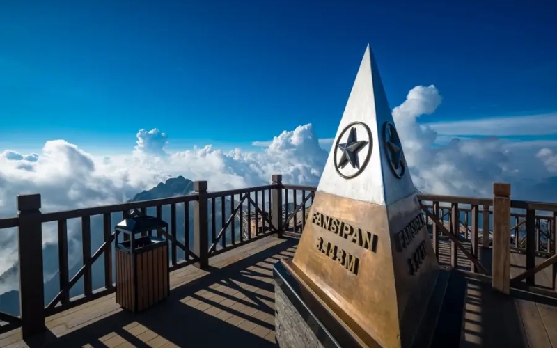 Monument marking the 3,143-meter summit of Fansipan, surrounded by clouds and a wooden observation deck, offering panoramic views from the highest peak in Indochina.