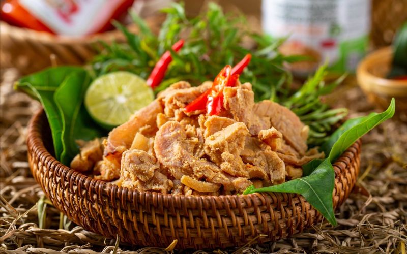 Basket of Thit Chua Thanh Son (fermented pork) garnished with red chili and fresh herbs, served on banana leaves