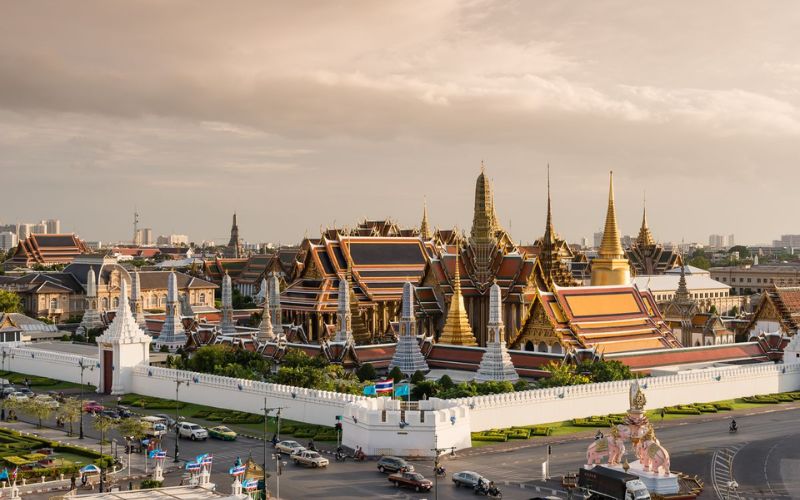 Panoramic view of the Grand Palace complex with golden spires at sunset