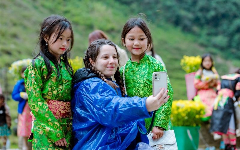Tourist interacting with ethnic minority children in Ha Giang Loop, showcasing local culture and community connection in northern Vietnam