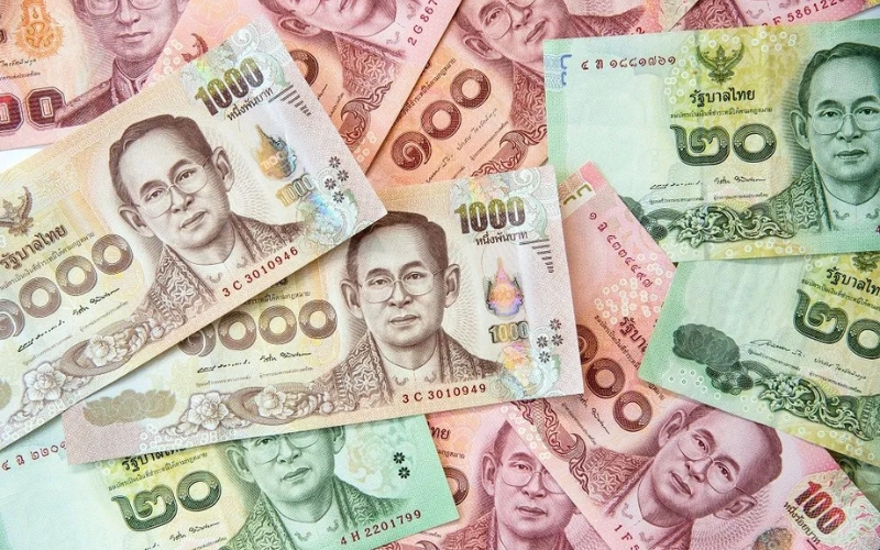 A close-up of Thai banknotes with the King’s portrait visible on each note.