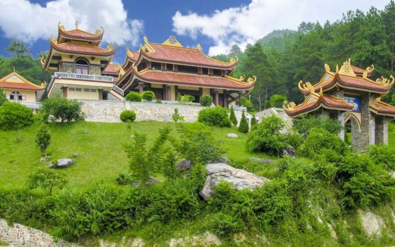 Tay Thien Pagoda in Tam Dao, Vietnam, featuring ornate golden-roofed buildings set on a lush green hillside under a bright blue sky