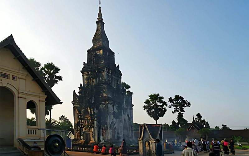 That Ing Hang Stupa, a prominent religious structure, with people gathered around it in an outdoor setting.