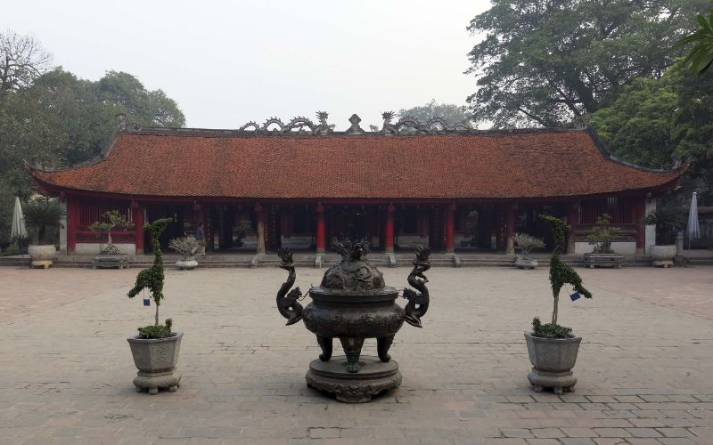 The grand entrance to the fourth courtyard, known as the Gate of Great Success (Dai Thanh Mon). Beyond the gate lies a spacious stone courtyard leading to the House of Ceremonies, featuring traditional architecture with ornate roof carvings and large ceremonial lanterns.