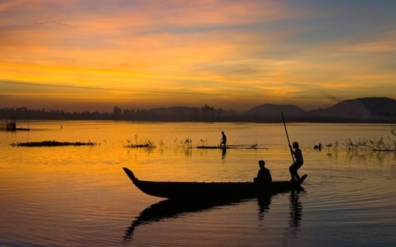 Wooden boats gliding through flooded fields during the rainy season in Đong Thap, reflecting the unique lifestyle of the Mekong Delta.