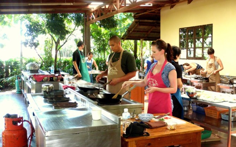 Participants preparing Thai dishes together at a traditional cooking school in Chiang Mai.