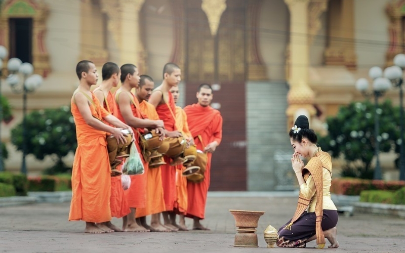 A quiet morning scene where locals greet monks during the alms-giving ritual.