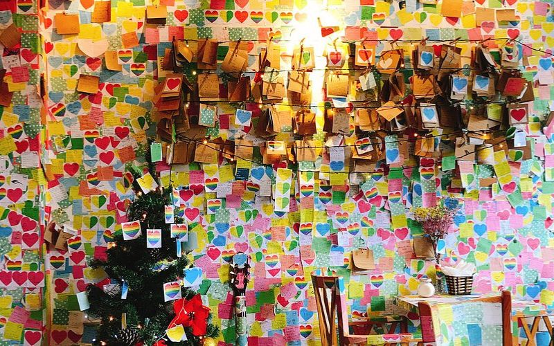 Colorful interior of The Note Coffee in Hanoi, with walls covered in handwritten sticky notes from visitors around the world