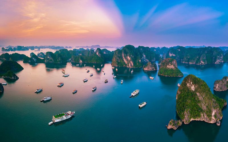 Scenic view of Ha Long Bay in Vietnam at sunset with cruise boats and limestone islands in calm blue water
