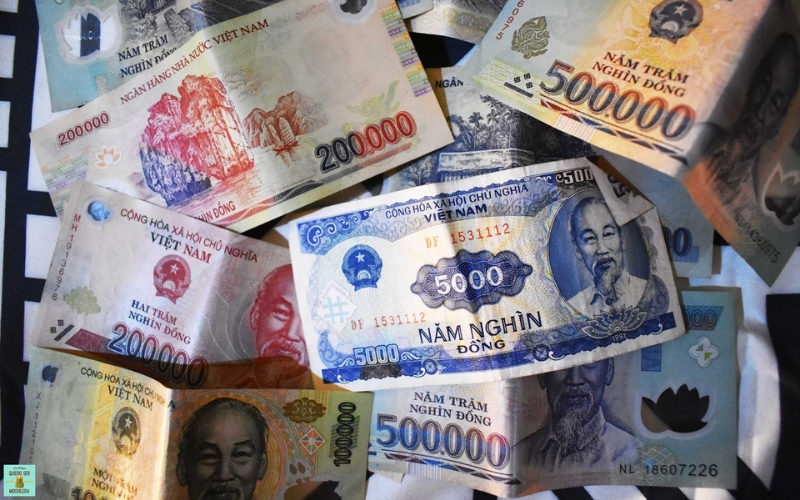 Assorted Vietnamese dong banknotes in various denominations scattered together, including 5,000, 200,000, and 500,000 VND notes.