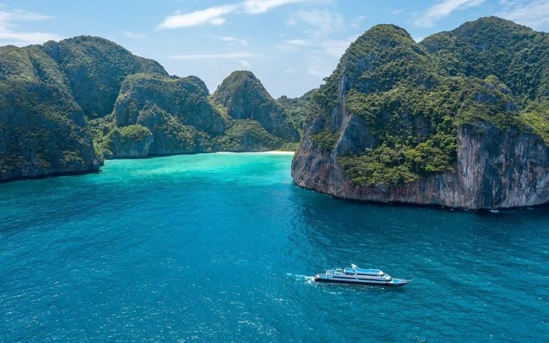 Luxury boat cruising near Maya Bay in Phi Phi Islands, Thailand, surrounded by turquoise waters and limestone cliffs
