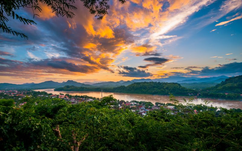 Panoramic view form Mount Phousi in Luang Prabang, Laos, showcasing the town, Mekong river and surrounding lush hills at sunset with vibrant skies in the background