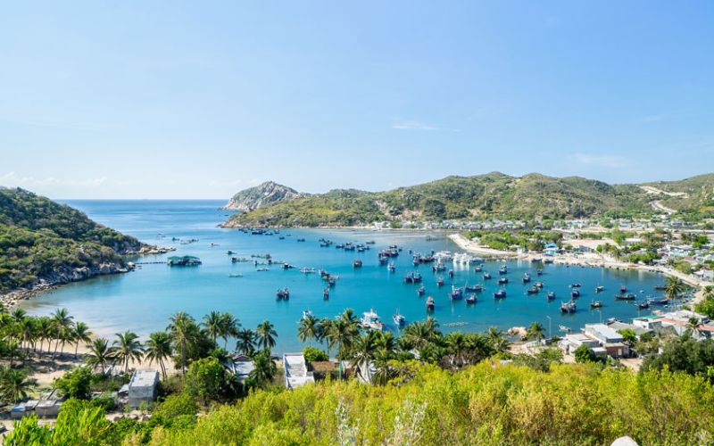 Scenic view of Vinh Hy Bay with turquoise water, fishing boats, and green hills in Khanh Hoa, Vietnam