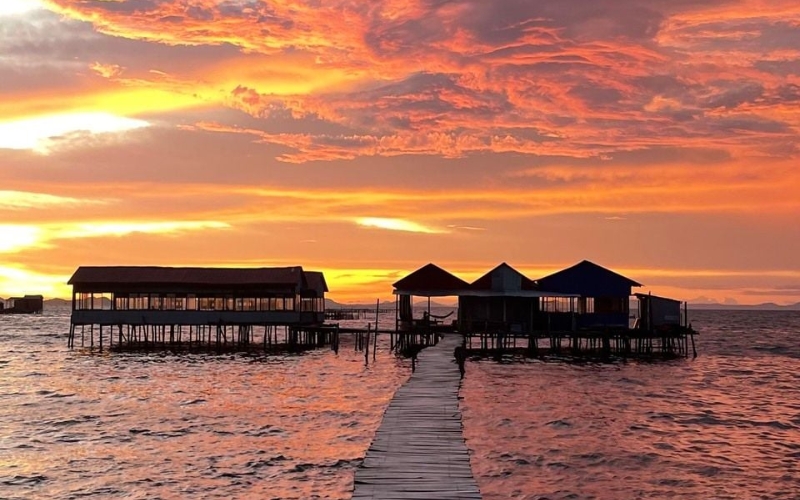 Long wooden pier stretching into the calm sea at Rach Vem Fishing Village, surrounded by stilt houses.