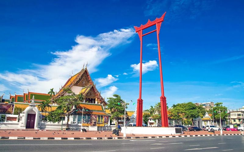 Wat Suthat Thepwararam and Giant Swing in Bangkok, Thailand, under clear blue sky, showcasing historic and cultural landmarks