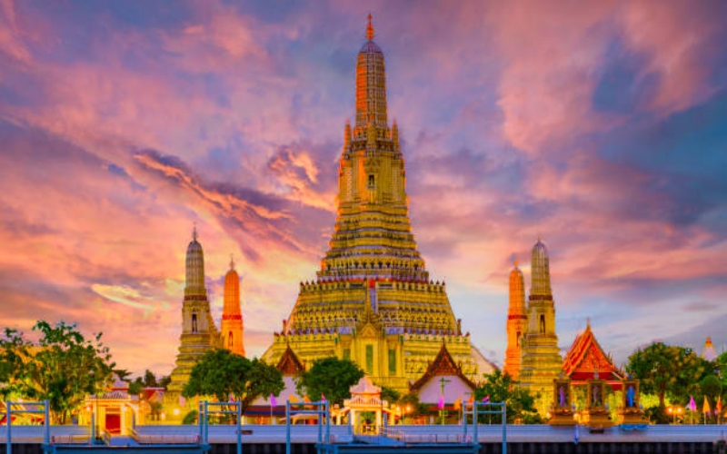 View of Wat Arun temple beautifully lit at sunset on the Chao Phraya River.