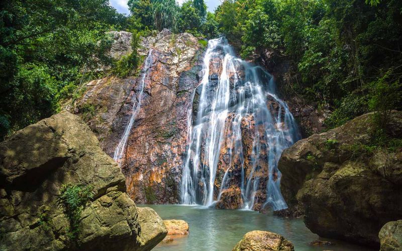 Scenic waterfall surrounded by lush jungle in Koh Samui, Thailand, a popular spot for hiking and nature exploration