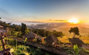 Sunrise over Yafu Village in Chiang Rai, Thailand, with traditional hill tribe huts and mountain landscape