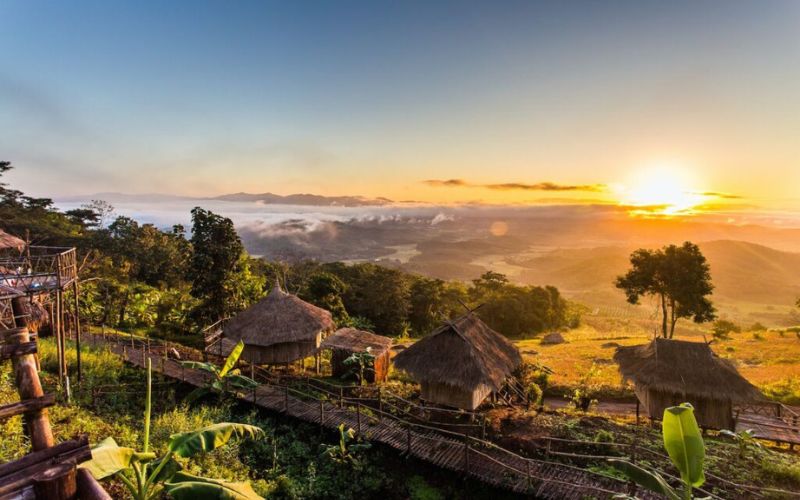 Sunrise over Yafu Village in Chiang Rai, Thailand, with traditional hill tribe huts and mountain landscape